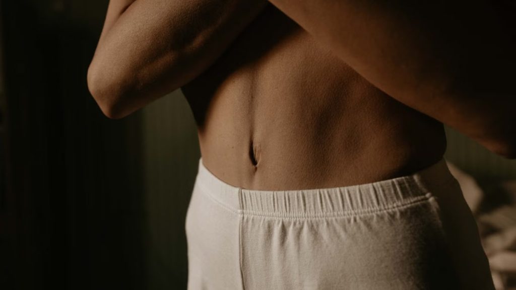 Artistic close-up of a person's torso in soft lighting, showcasing natural skin texture and detail.